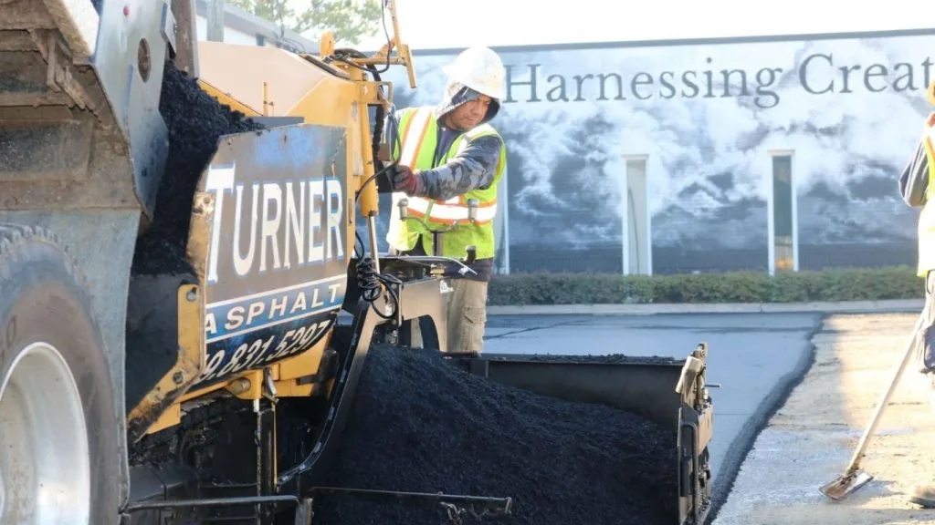 paving company employee on a large machine completing an asphalt repaving project